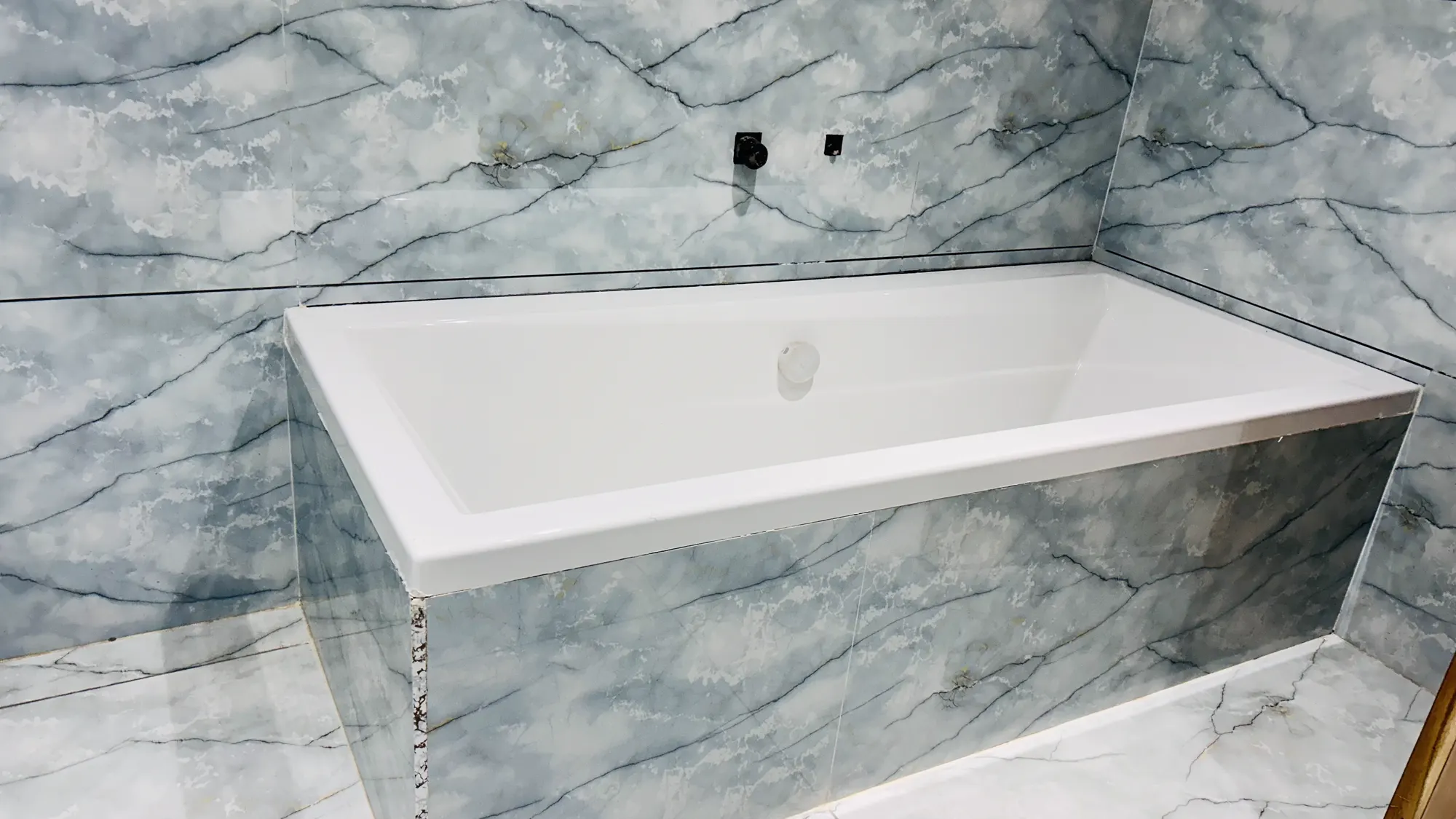 Marble-finish bathroom with bathtub at Jay Mahal Hotel