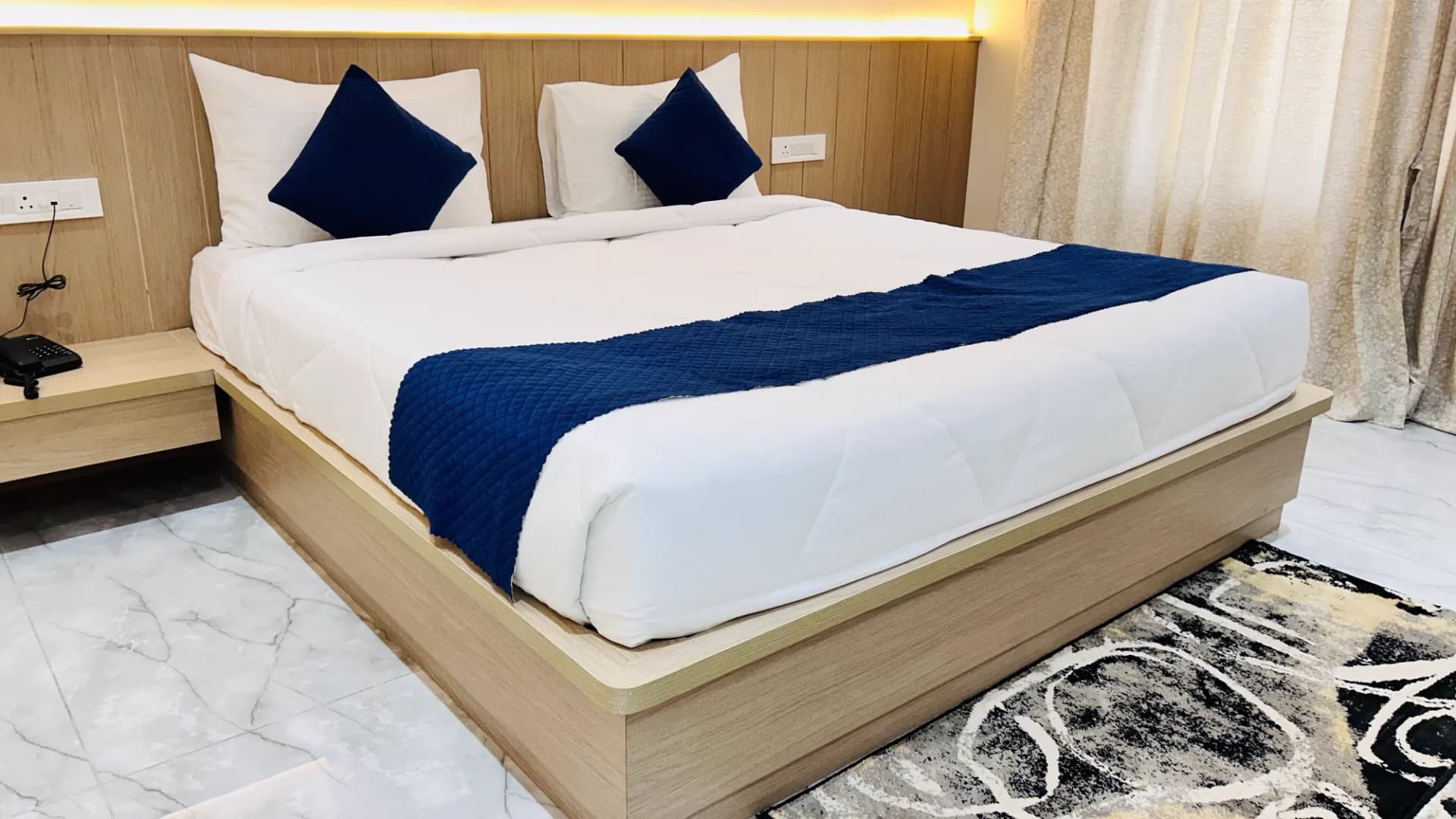 Neatly made double bed with navy runner at Jay Mahal