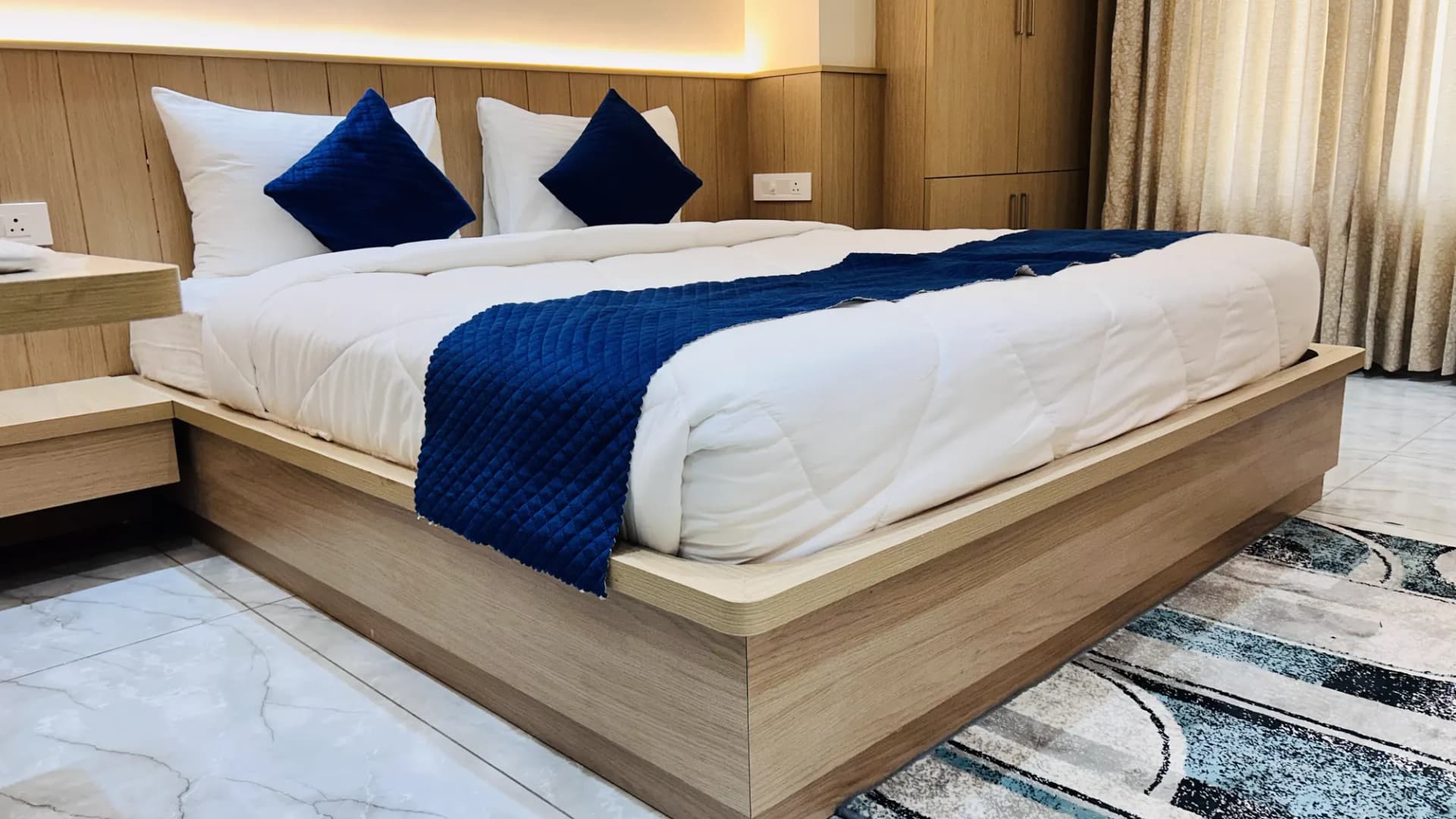 Spacious double room with navy-and-white linen at Jay Mahal